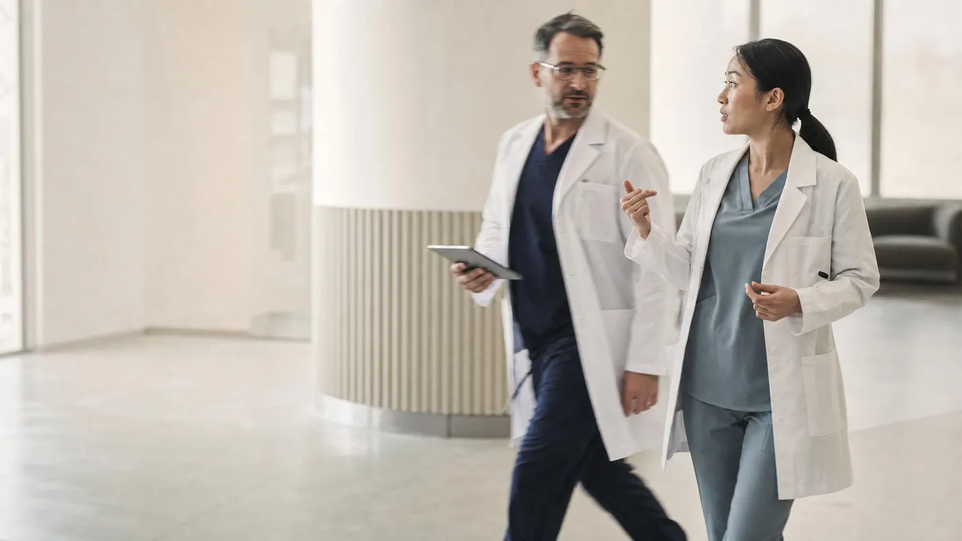 Two clinicians in conversation walking through a modern clinic