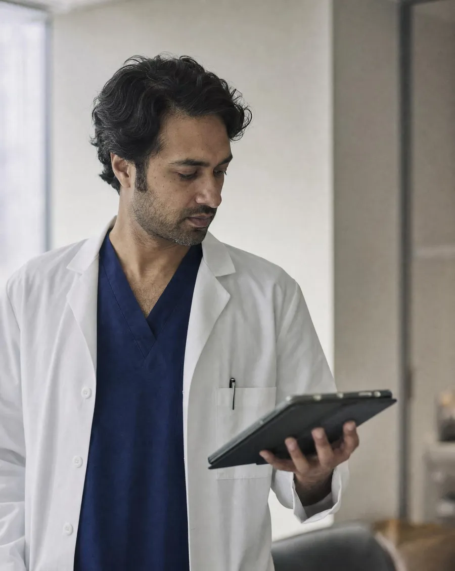 A clinician reviewing notes on a tablet in a modern clinic